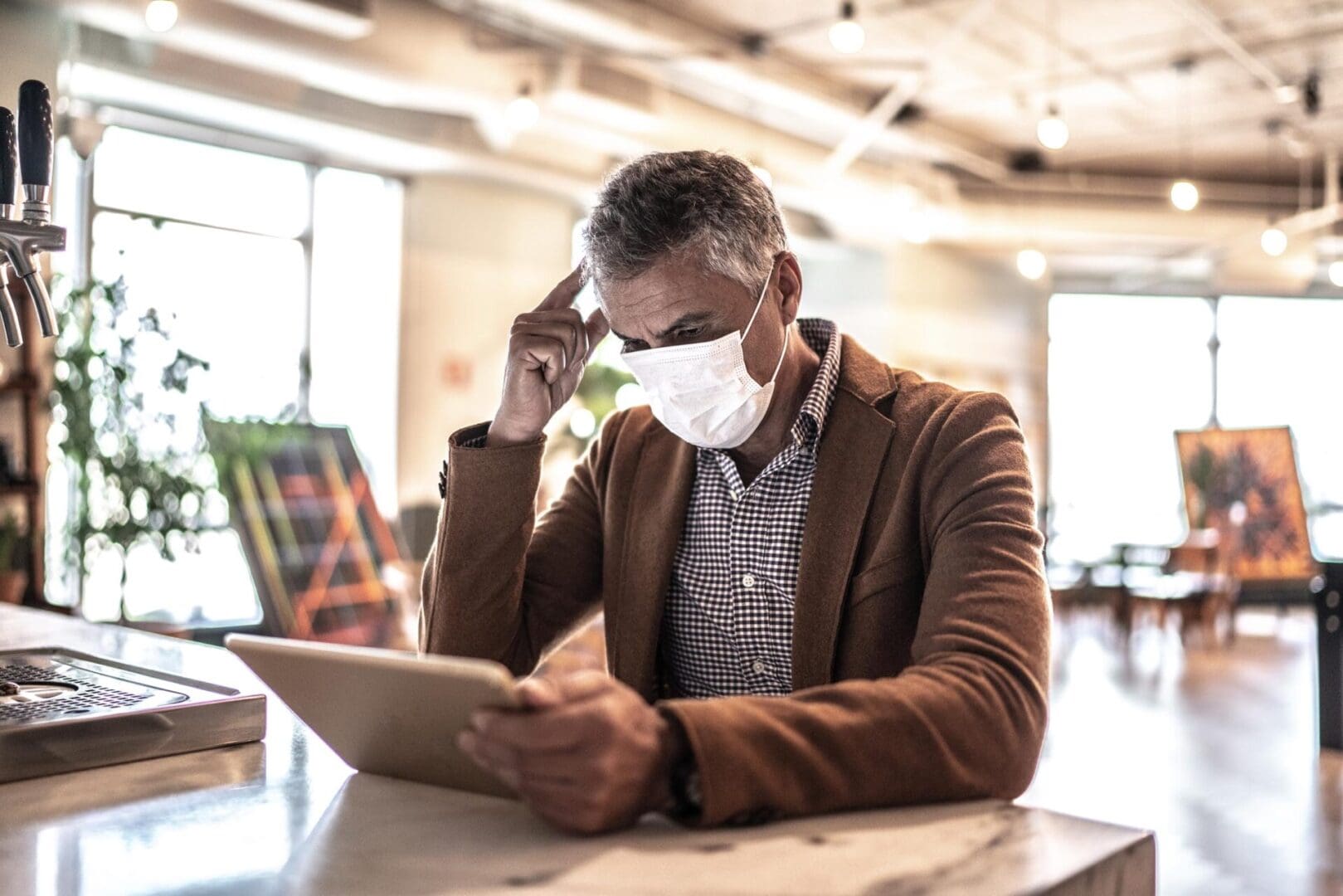 A man wearing a mask while looking at his tablet.