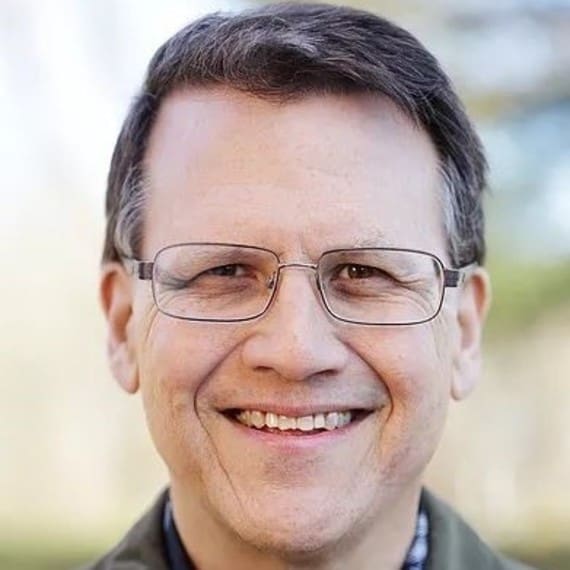 A man with glasses smiling for the camera.