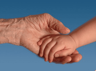 A child and an adult holding hands in front of the sky.