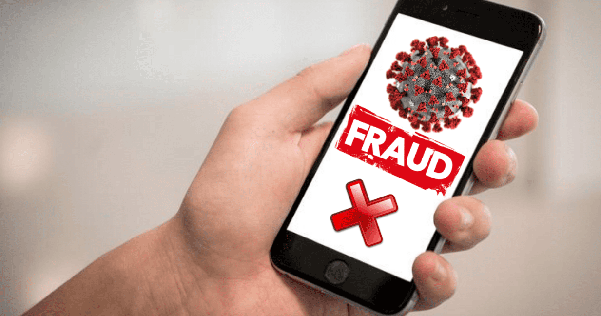 A person holding a cell phone with fraud on it.