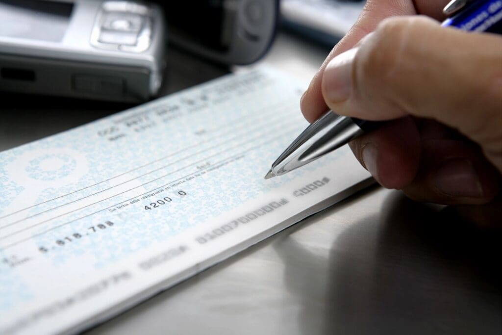 A person writing on a check with a pen.