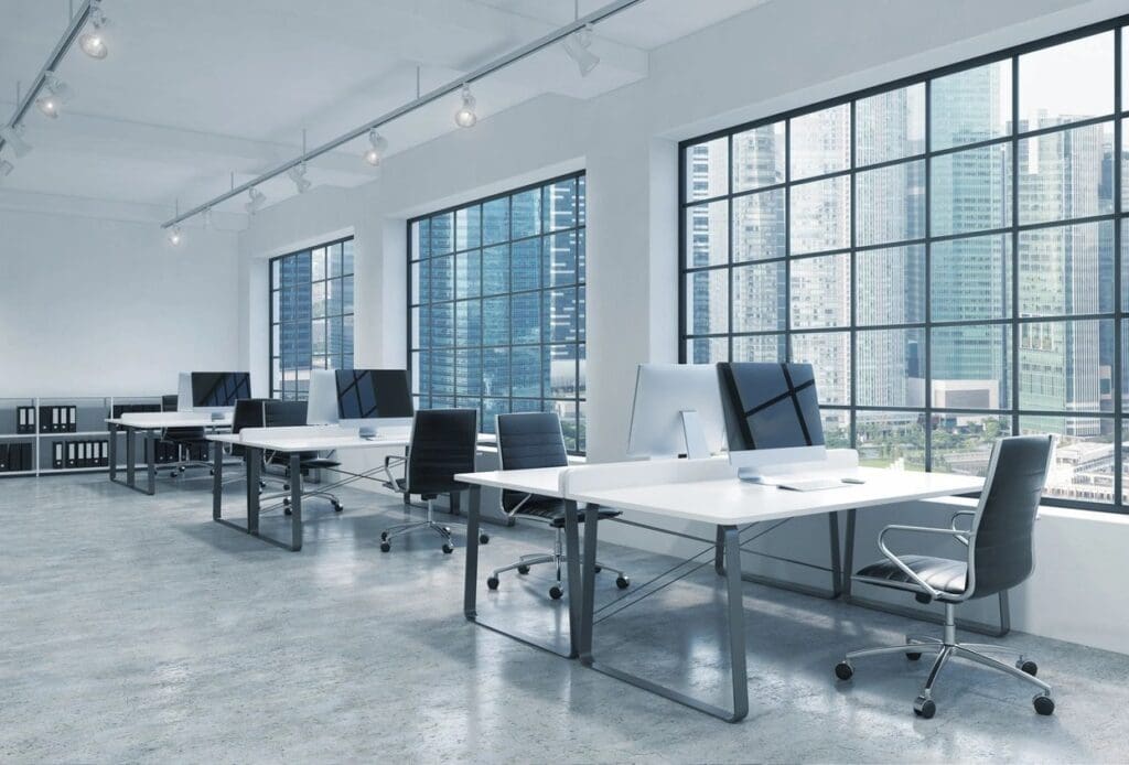 A row of desks with computers on top.