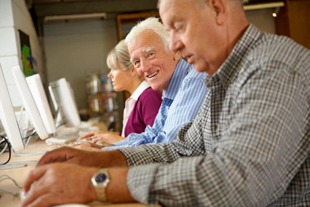 A group of people sitting at computers in front of each other.