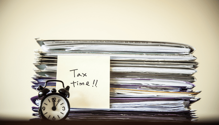 A clock sitting on top of papers next to a pile of papers.