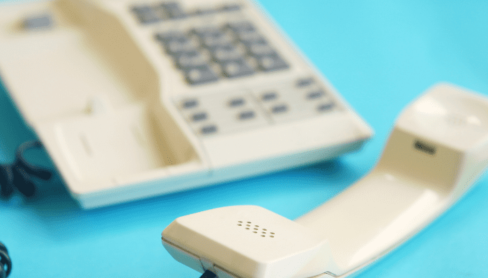 A telephone and a remote control on a table.