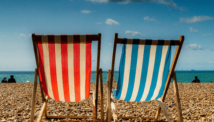 Two beach chairs are sitting on the sand.