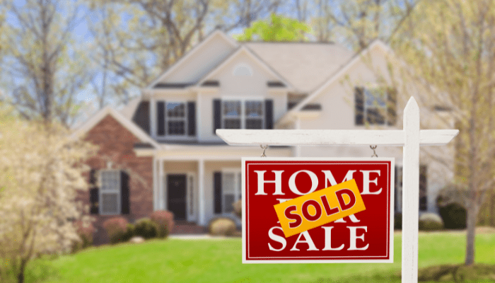 A red sold sign sitting in front of a house.