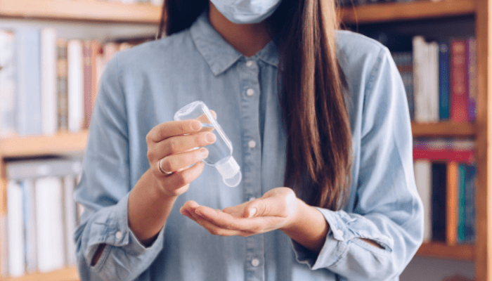 A woman holding a bottle of hand sanitizer.