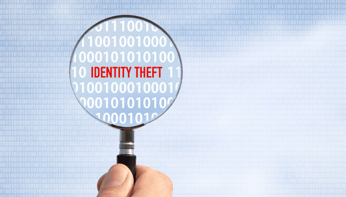 A magnifying glass is held over the words identity theft.