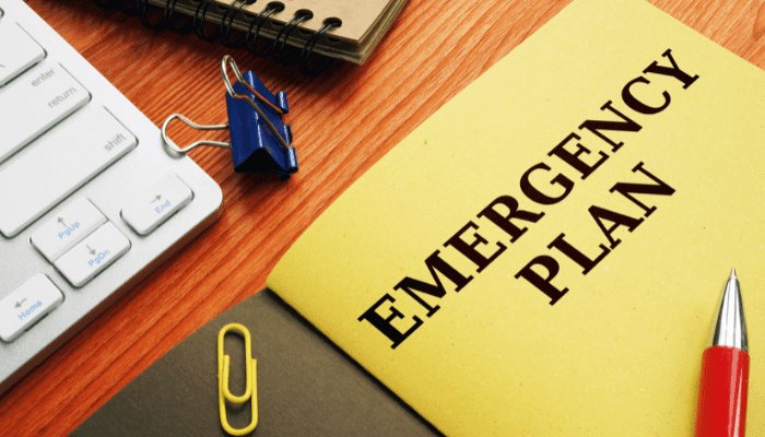 A yellow emergency plan book sitting on top of a wooden desk.