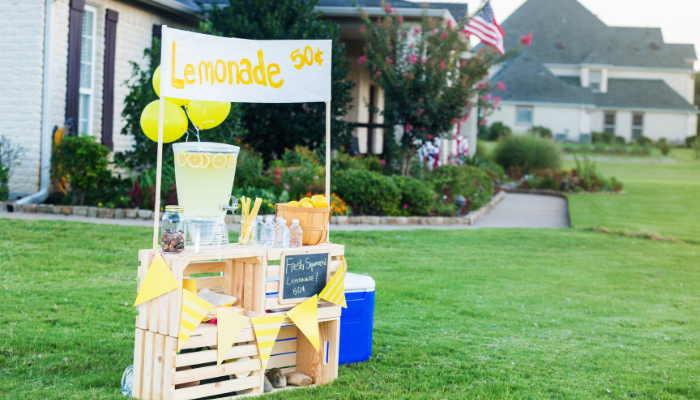 A lemonade stand is set up in the grass.