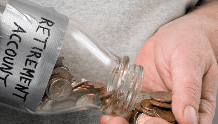 A person holding a jar of coins in their hand.