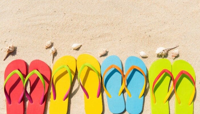 A row of flip flops sitting on top of the sand.