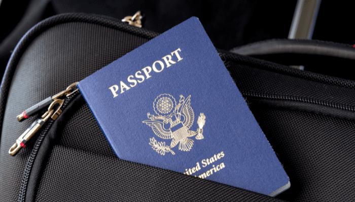 A passport sitting on top of a suitcase.