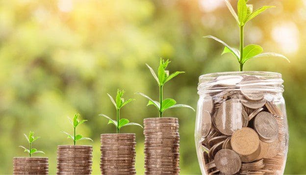 A jar of coins and some plants growing out of it.