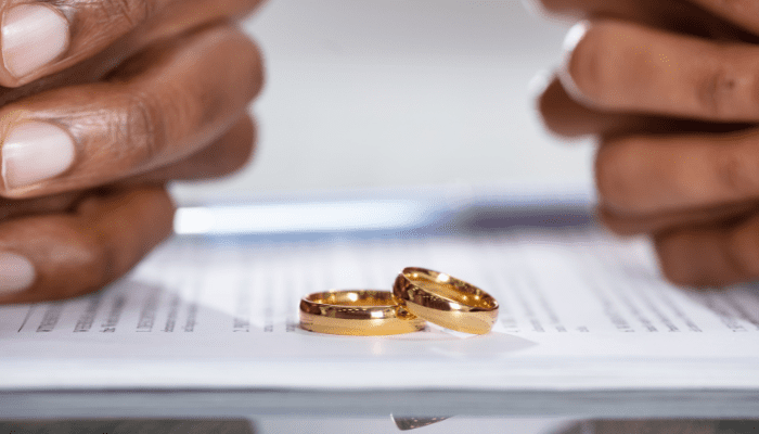Hands with wedding rings on paperwork.