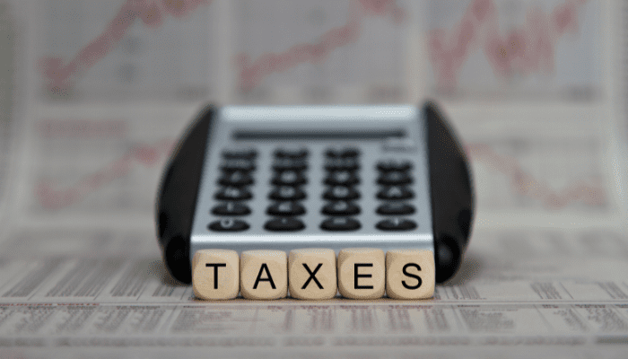 Calculator with "TAXES" on wooden blocks.