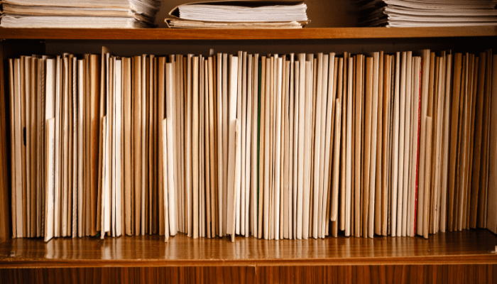 Books and files on a wooden shelf.